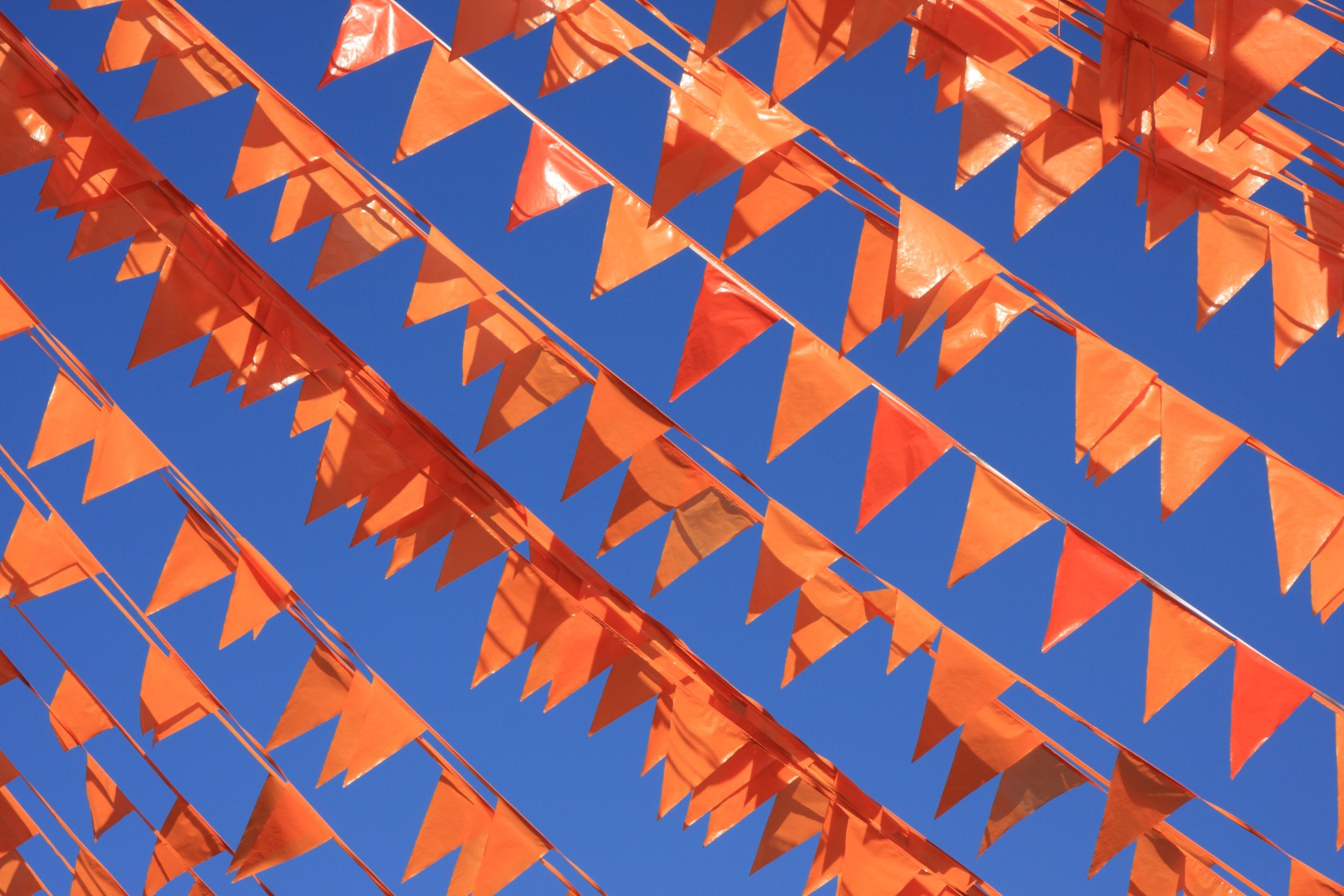 Orange flags against a blue sky during the soccer world cup.